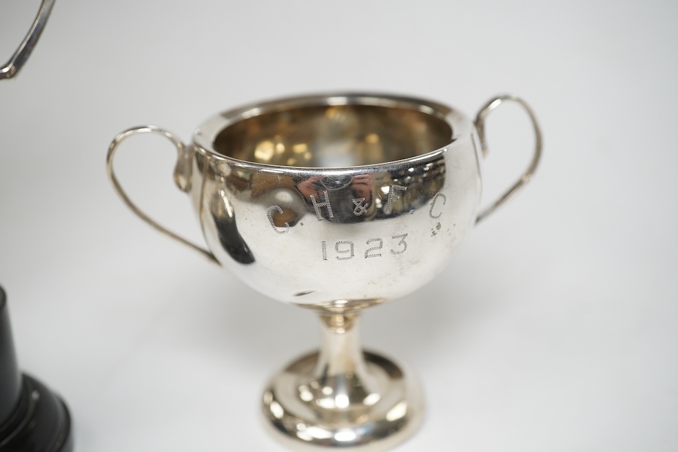 A pair of Edwardian silver dwarf candlesticks, of tapering design, C.S Green & Co, Birmingham, 1908, 13.2cm, together with four small silver trophy cups, a silver napkin ring and a plated trophy cup. Condition - poor to